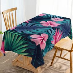 the table cloth has pink flowers and green leaves on it, along with a wooden chair