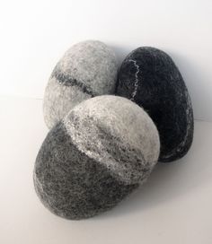 three gray and black balls sitting next to each other on top of a white surface