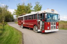 a red and white bus traveling down a rural road