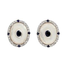 Handcrafted from 14-karat gold, these stud earrings are set with .40 carats of diamonds, 4.55 carats Mother of Pearl and .65 carats sapphire. FOLLOW MEGHNA JEWELS storefront to view the latest collection & exclusive pieces. Meghna Jewels is proudly rated as a Top Seller on 1stDibs with 5 star customer reviews. All items manufactured by us are handmade and can be customized or redesigned. Composition Size-17X14 MM Total Weight-6.68 Gold Weight(Gms)-5.56 Diamond Wt(Cts)-0.4 Mother of Pearl Wt(Cts) Luxury Oval Sapphire Diamond Earrings, Luxury Oval Diamond Earrings With Accents, Luxury White Gold Sapphire Diamond Earrings, Luxury Oval Diamond Earrings With Gemstones, Fine Jewelry Sapphire Diamond Earrings, Sapphire Diamond Accented Earrings In Fine Jewelry, Luxury Sapphire Diamond Earrings For Anniversary, Oval Fine Jewelry Diamond Earrings With Single Cut Diamonds, Sapphire Diamond Earrings With Accents