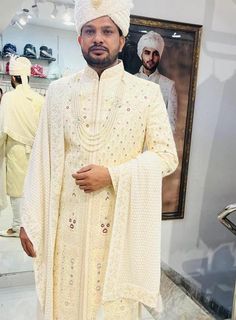 a man in a white outfit standing next to a painting