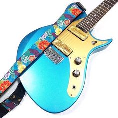 a blue guitar strap that has flowers on it and is attached to an electric guitar