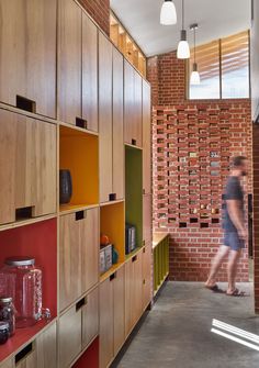 a woman walking down a hallway next to a brick wall with shelves on both sides