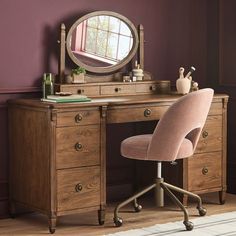 a desk with a chair and a mirror on it in front of a purple wall