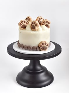 a cake with white frosting and chocolate chips on top sitting on a black stand