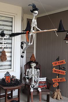 a skeleton sitting on a chair in front of a house decorated with halloween signs and decorations