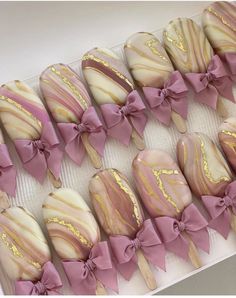 a box filled with lots of pink and gold decorated cookies next to each other on top of a table