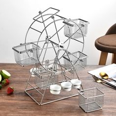 a metal ferris wheel sitting on top of a wooden table next to some strawberries