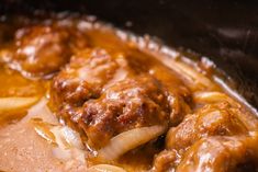 meatballs and onions are being cooked in the slow cooker with gravy