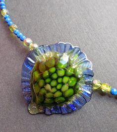 "The lovely glass pendant was made by Christian Luginger, a local, award winning glass-blower. I chose green Swarovski beads and lapis to complement the colors in the pendant.  The cones and clasp are sterling silver. The necklace is 10\" long.  This is a one of a kind necklace." Blue-green Round Beads Jewelry Gift, Blue-green Round Beads Jewelry For Gifts, Green Glass Jewelry With Faceted Beads, Green Czech Glass Jewelry, Artisan Green Czech Glass Beaded Necklaces, Artisan Green Beaded Necklace With Czech Glass, Green Recycled Glass Round Bead Jewelry, Artisan Green Czech Glass Beaded Necklace, Green Beaded Jewelry From Recycled Glass