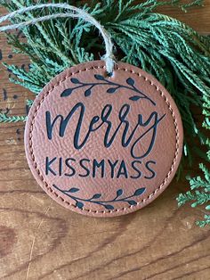 a leather ornament with merry kissmyas on it hanging from a tree