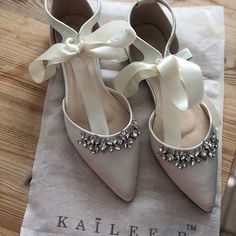 a pair of white high heeled shoes sitting on top of a napkin