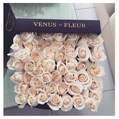 a box filled with flowers sitting on top of a floor next to a sign that says venus and fleur