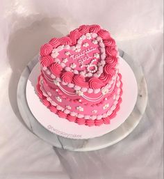 a pink heart shaped cake sitting on top of a white plate