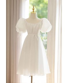 a white dress on a mannequin stand in front of a window