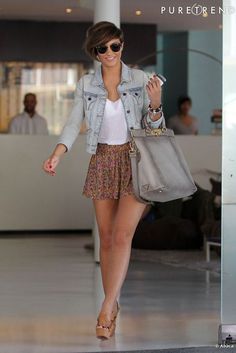 a woman walking through an airport carrying a purse