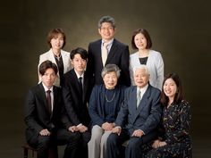 a group of people posing for a photo in front of a dark background with one person wearing a suit and tie