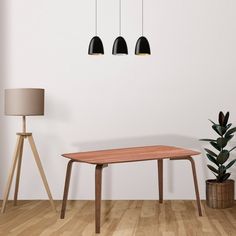 an empty room with three lamps hanging from the ceiling and a wooden table in front of it