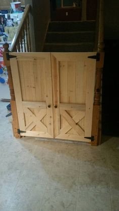 an open wooden door sitting on top of a tile floor next to a stair case