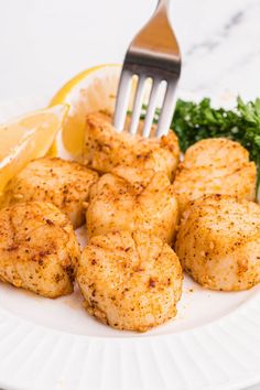 a white plate topped with chicken cutlets and lemon wedges