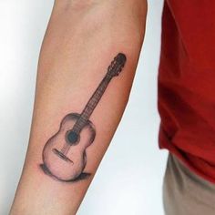 a man with a guitar tattoo on his arm is holding the other arm in one hand