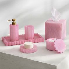 pink bathroom accessories including soap, toothbrush and soap dispenser on white surface