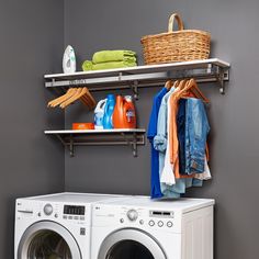 a washer and dryer in a laundry room with clothes hanging on the rack