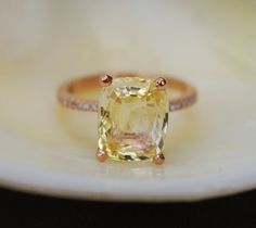 a yellow diamond ring sitting on top of a white plate