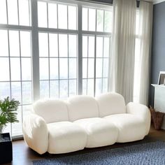 a living room filled with furniture next to large windows on top of a hard wood floor