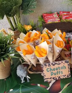 a table topped with lots of different types of food next to potted plants and signs