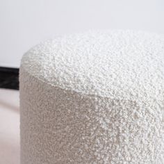 a white round ottoman sitting on top of a hard wood floor