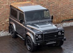 a grey land rover parked in front of a brick wall