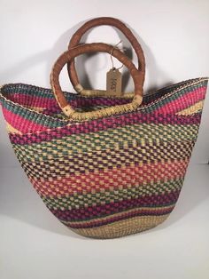 U-shopper basket is the perfect tote, beach bag, shopper, everyday bag, or home decor basket.  The beautiful bolga baskets are hand-woven in small villages of Ghana, a tradition passed down from generation to generation. They are woven out of renewable resource elephant grass, which grow abundantly in the region. Each basket is hand woven and 100% unique! The leather handle is treated using an all-natural process (either dyed and oiled or painted). Note that handle colors will vary and may range from black to an oiled red color.  Variations are to be expected and treasured. Baskets are sturdy, strong, and flexible. If properly cared for, your basket will live a long life. Details Large U-Shopper basket measures approx 16-18 inches across and 11-13" deep.   The basket is washable and collap Casual Basket Beach Bag For Shopping, Large Capacity Basket-shaped Bucket Bag For Shopping, Large Capacity Basket Bucket Bag For Shopping, Shopping Bucket Beach Bag With Handles, Brown Basket Beach Bag With Rolled Handles, Eco-friendly Shopping Beach Bag With Handles, Eco-friendly Beach Bag For Shopping, Large Capacity Multicolor Bucket Straw Bag, Eco-friendly Shopping Beach Bag