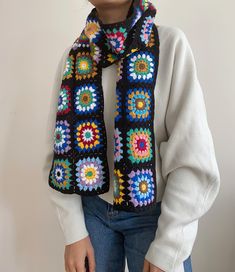 a woman wearing a black crocheted scarf with multicolored flowers on it