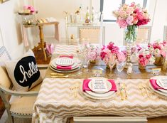 the table is set with pink flowers and gold place settings for an elegant wedding reception