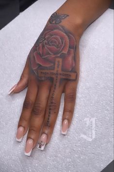 a woman's hand with a cross and rose tattoo on the middle of it