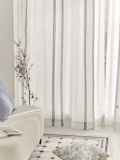 a white couch sitting in front of a window next to a rug on top of a wooden floor