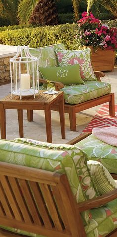 the patio furniture is decorated with green and pink flowers in vases on top of them