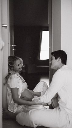 a man and woman sitting on the floor in front of a door looking at each other