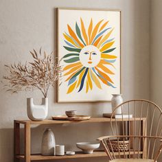 an art print hangs on the wall above a wooden table with chairs and vases