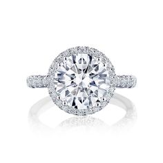 a diamond engagement ring with diamonds on the band and an oval center stone surrounded by pave