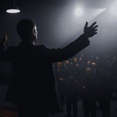 a man standing in front of a crowd holding his hands up