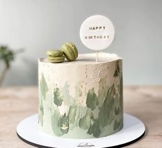 a decorated birthday cake sitting on top of a wooden table next to a green plant