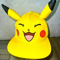 a yellow pokemon pikachu hat with black horns and red eyes on it's face