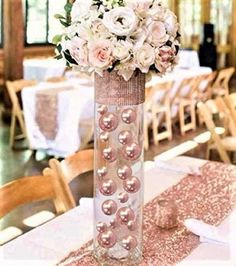 a tall vase filled with flowers and pearls on top of a table covered in pink sequins