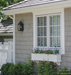 a house with a white picket fence and window boxes on the side of the house