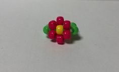 a colorful flower ring sitting on top of a white table next to a green and yellow object