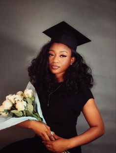 a woman in a graduation cap and gown holds flowers while posing for a photo with a bouquet of roses