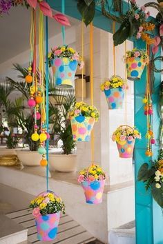 colorful flower pots hanging from the side of a building with flowers in them and other decorations