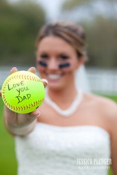 a woman holding a softball with the words i love you dad written on it in front of her face